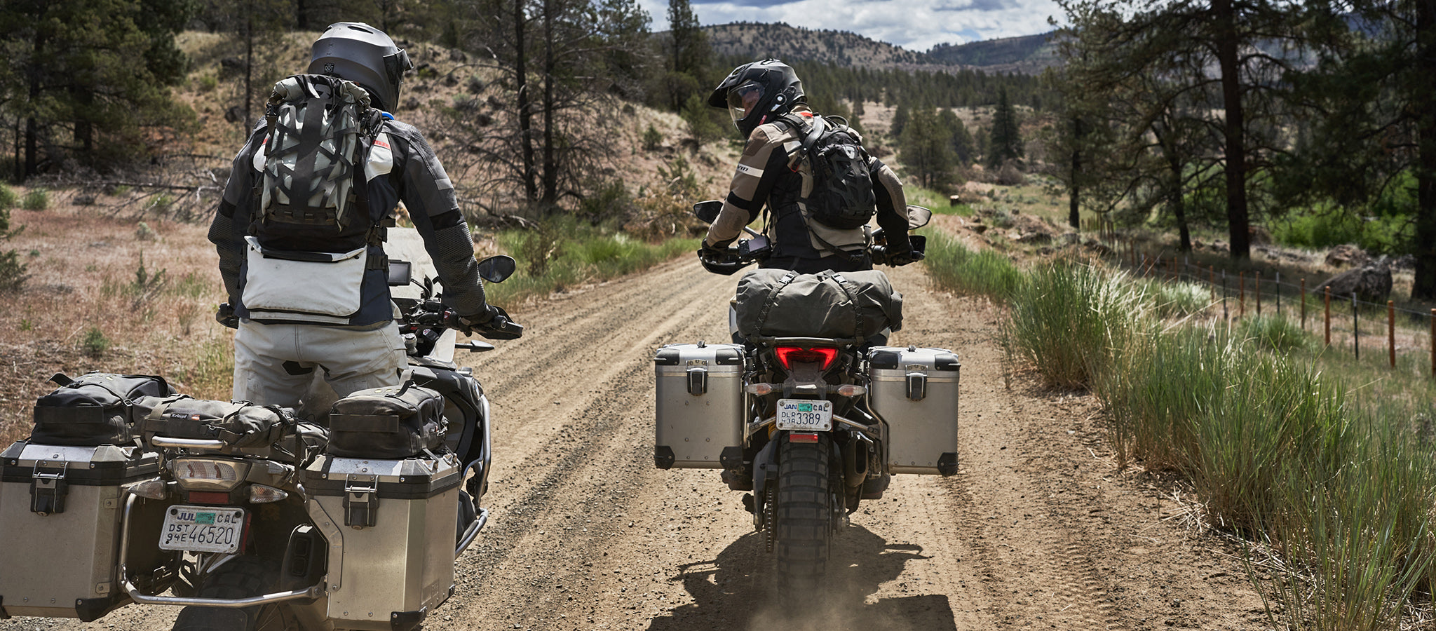 Lifestyle image of two motorcyclists wearing REV'IT! motorcycle gear, while riding their adventure bikes on a gravel road