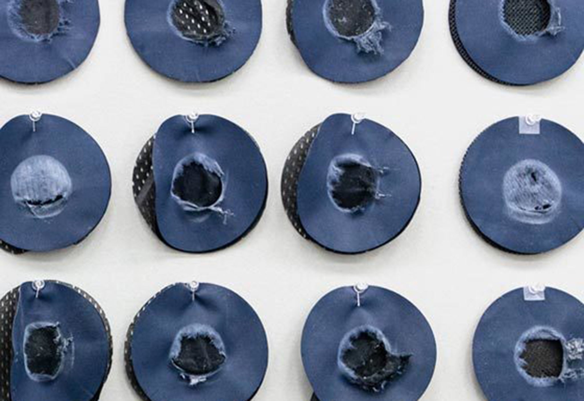 Close-up of denim material specimens pinned to the wall of the REV'IT! Lab Impact Abrasion Resistance machine