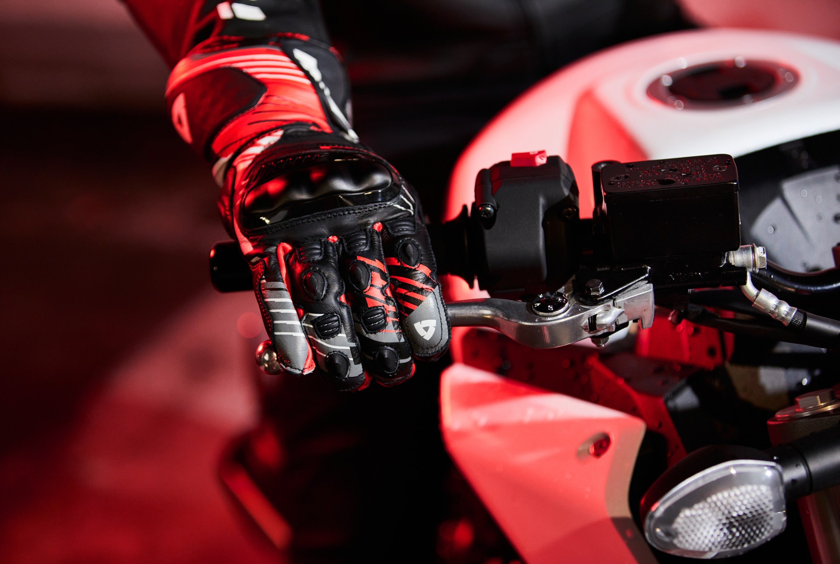 Close-up image of a motorcyclist pulling the front brake lever while wearing a pair of REV'IT! motorcycle gloves