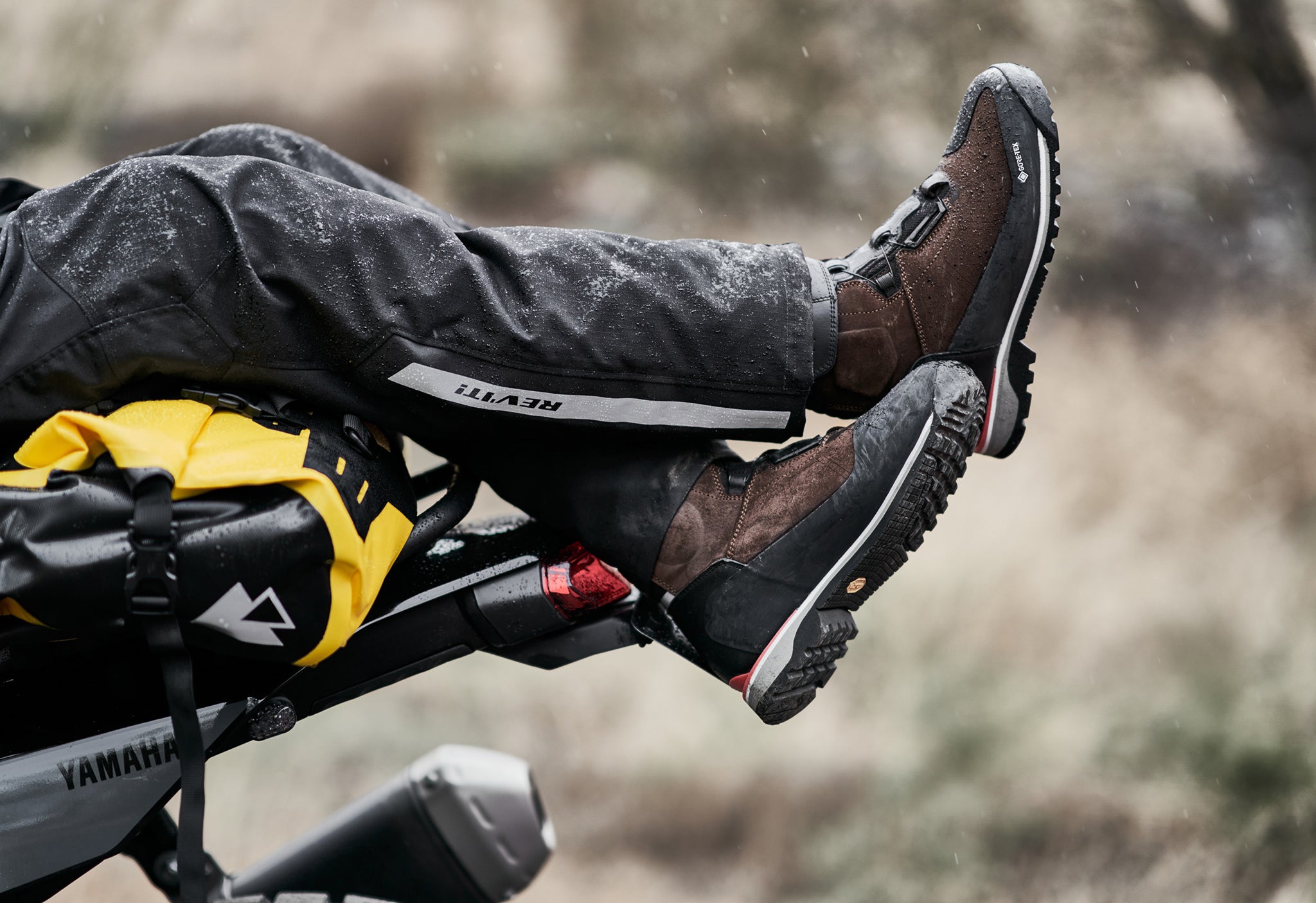 Close-up lifestyle image of a motorcyclist wearing a pair of REV'IT! motorcycle boots, while reclining on a motorbike