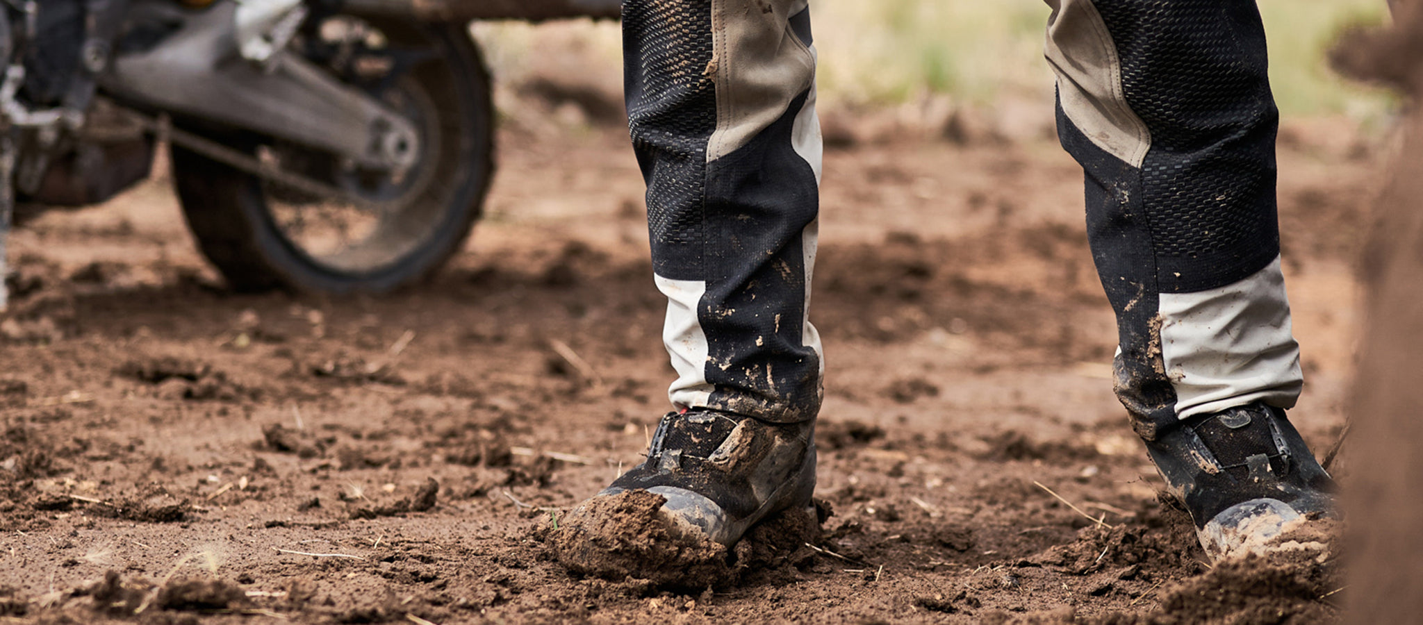 Cropped image of a motorcyclist wearing muddy REV'IT! motorcycle boots and pants